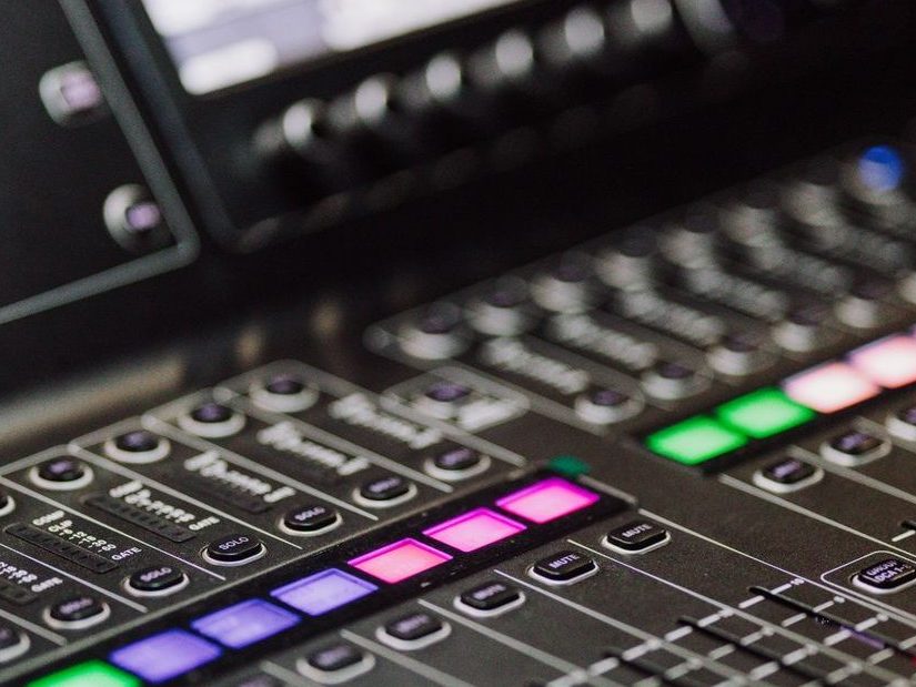 A detailed view of a professional audio mixing console with colorful LED indicators, ideal for music production environments.